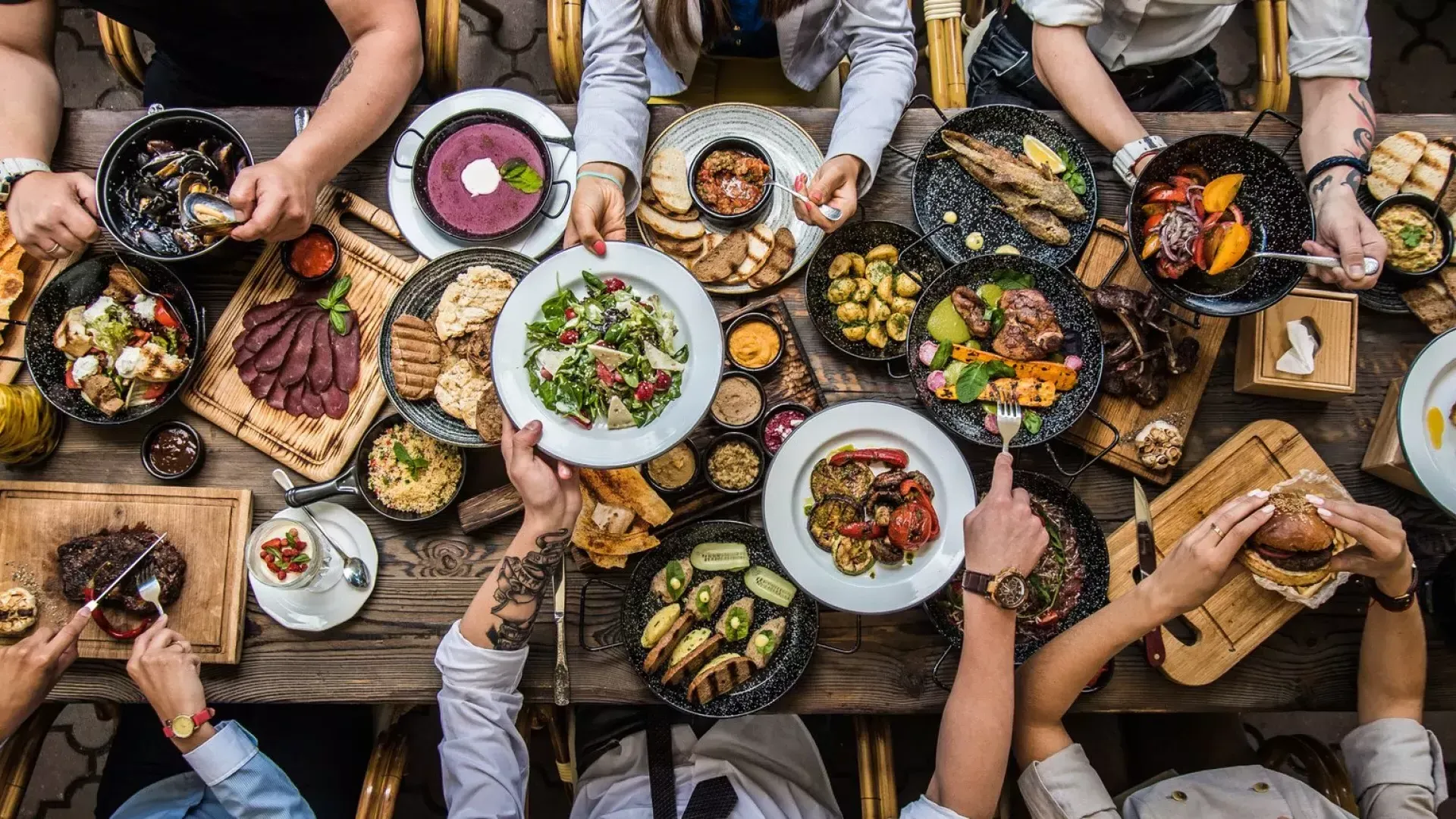 People sitting at a dining table, sharing 食物.