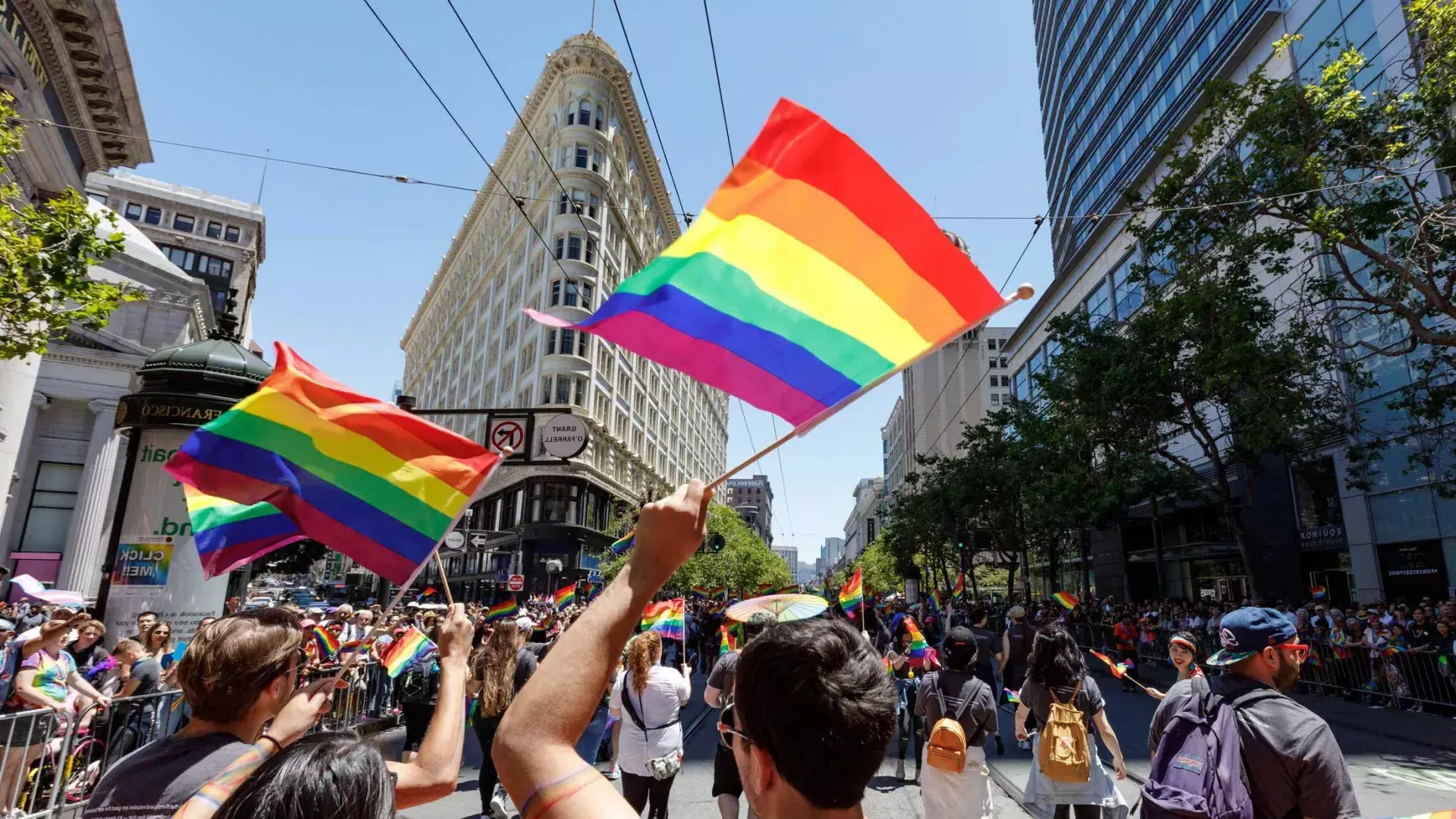 La gente que camina en el desfile del 贝博体彩app的骄傲 ondea banderas del arco iris.